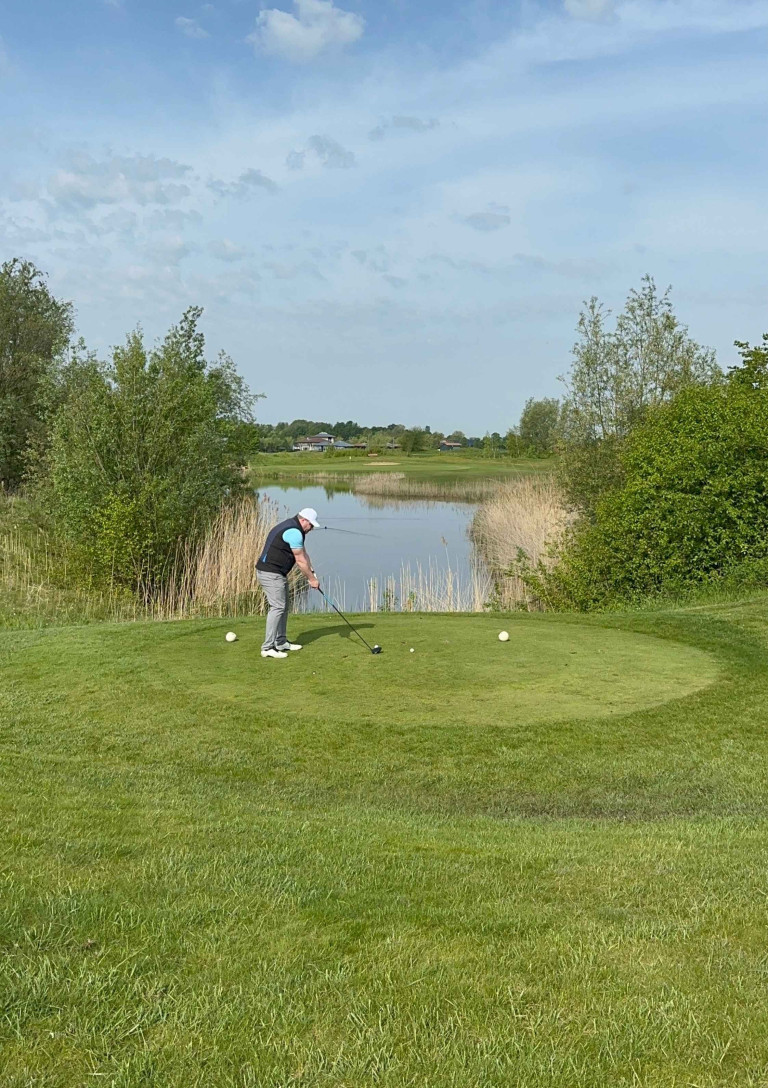 Golfer beim Abschlag auf einem gepflegten Golfplatz am Wasser – grasgefluster-4