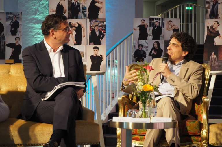 Podiumsdiskussion mit Blumenarrangement und Fototafeln im Hintergrund bei einer Nobilis-Veranstaltung