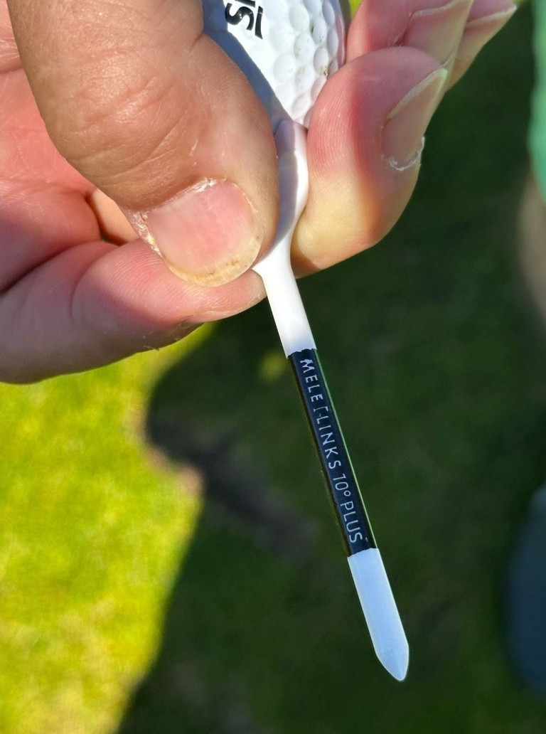 Nahaufnahme eines Golf-Tees mit der Aufschrift 'MELE LINKS 70° PLUS' auf grünem Rasen