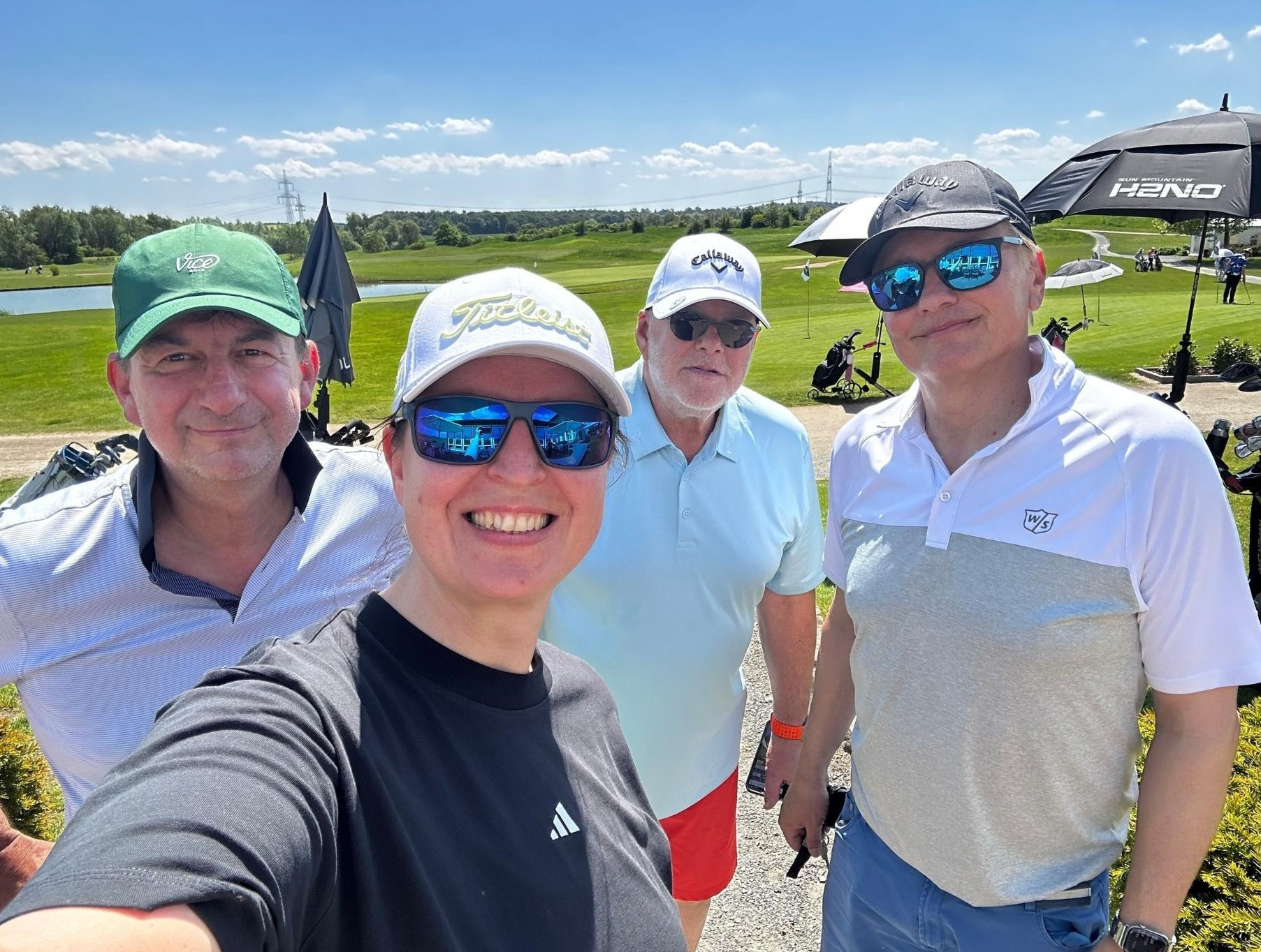 Gruppe von vier Personen beim Golfen auf einer sonnigen Golfanlage – bilder nobilis web