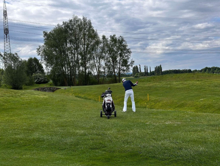 Golfer beim Abschlag auf dem Nobilis Golfplatz mit Golfbag und grüner Landschaft