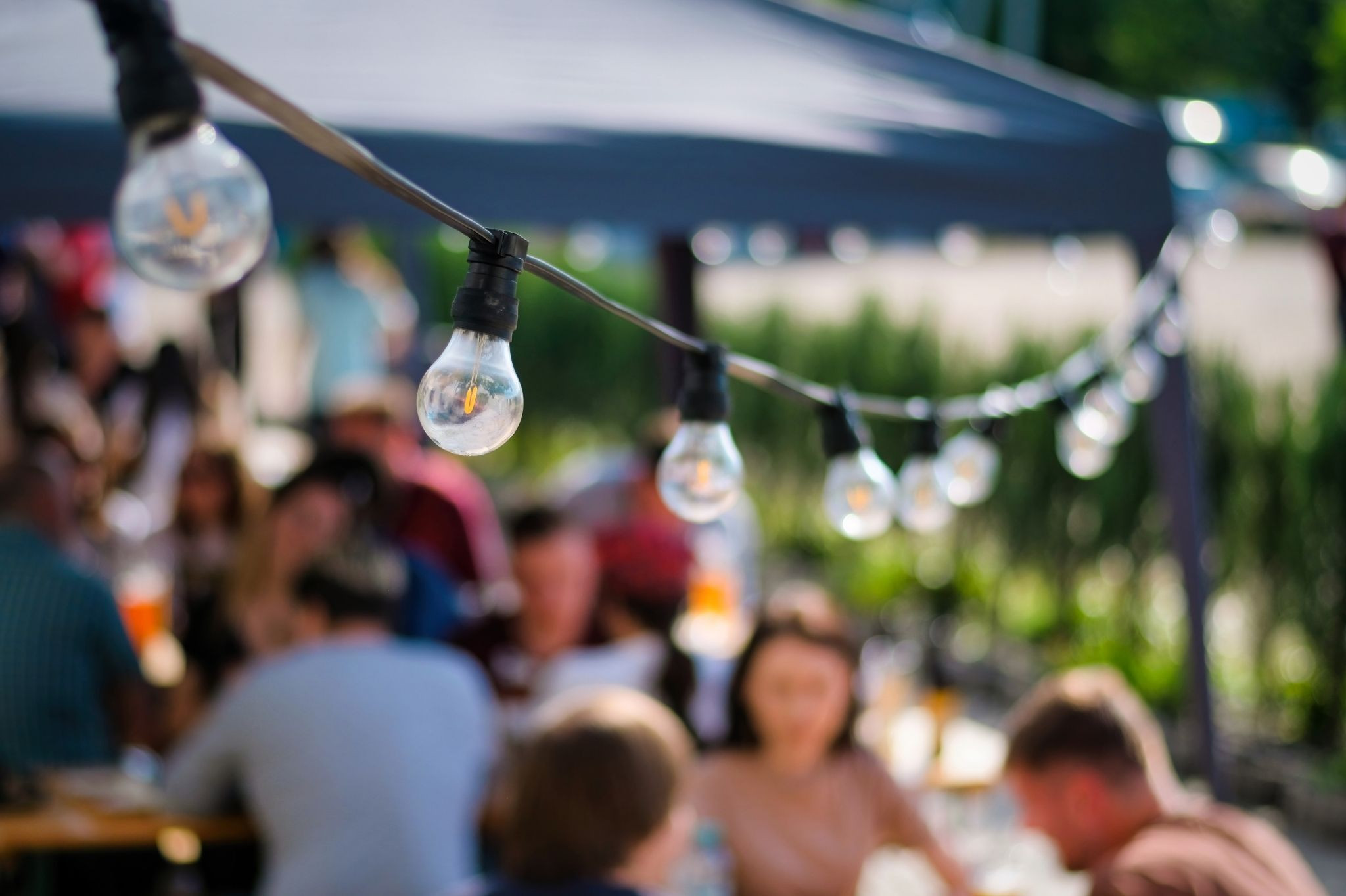 Gemütlicher Biergarten mit Lichterkette und Menschen im Sommer