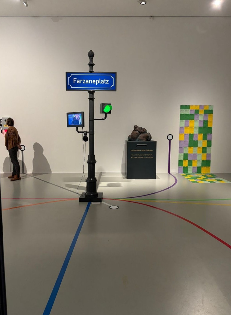 Kunstinstallation mit Farzaneplatz-Schild, Ampel und moderner Kunst im Ausstellungsraum, aufgenommen für nobilis web.