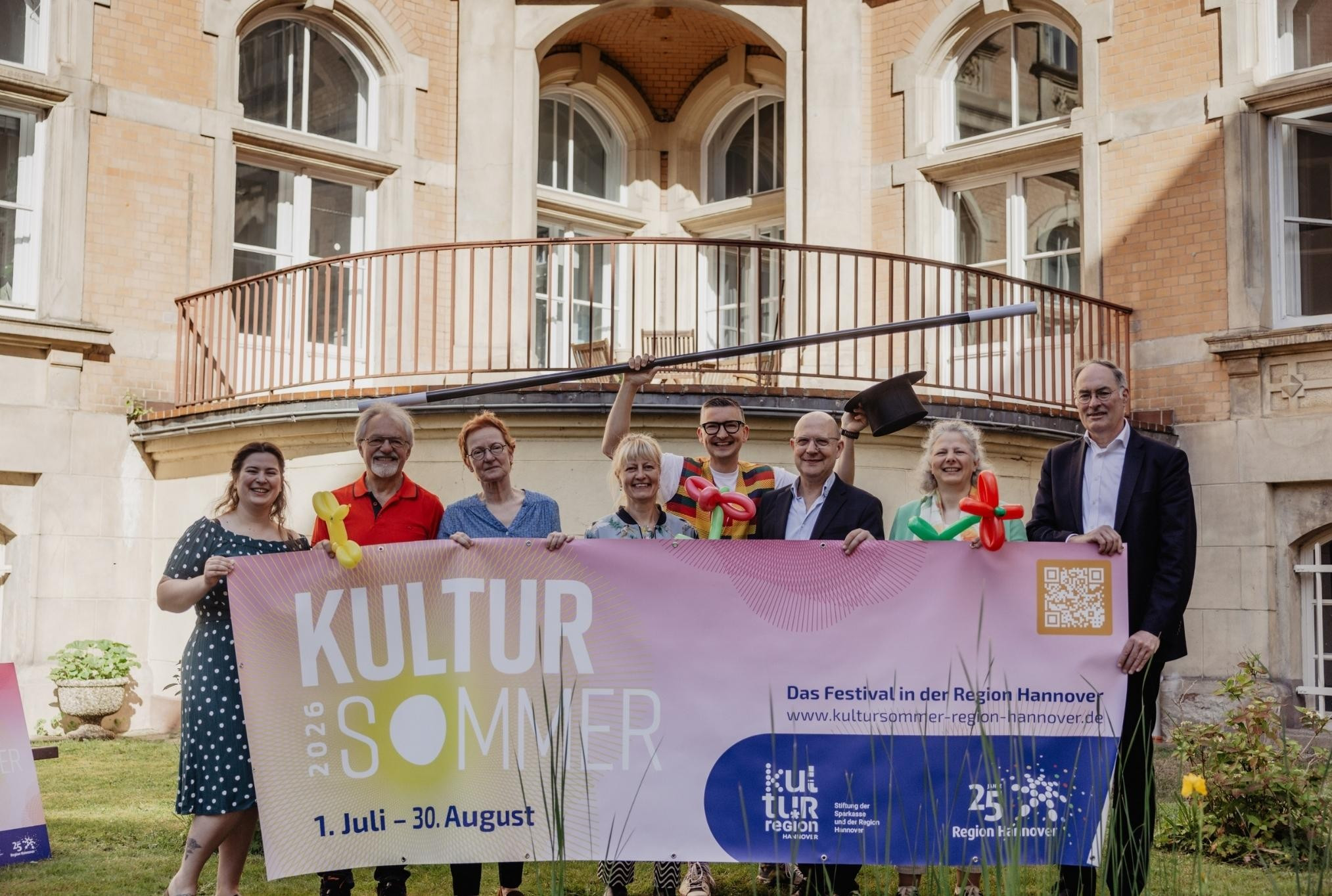 Gruppenfoto vor historischer Fassade beim Kultursommer 2026 in der Region Hannover mit Banner und Luftballons