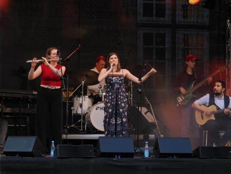 Nobilis Band live auf der Bühne – Konzertfoto mit Sängerin, Flötistin, Bassist und Schlagzeuger Band Nobilis live auf der Bühne bei einem Konzert, Sängerin mit Mikrofon, Flötistin, Bassist und Schlagzeuger