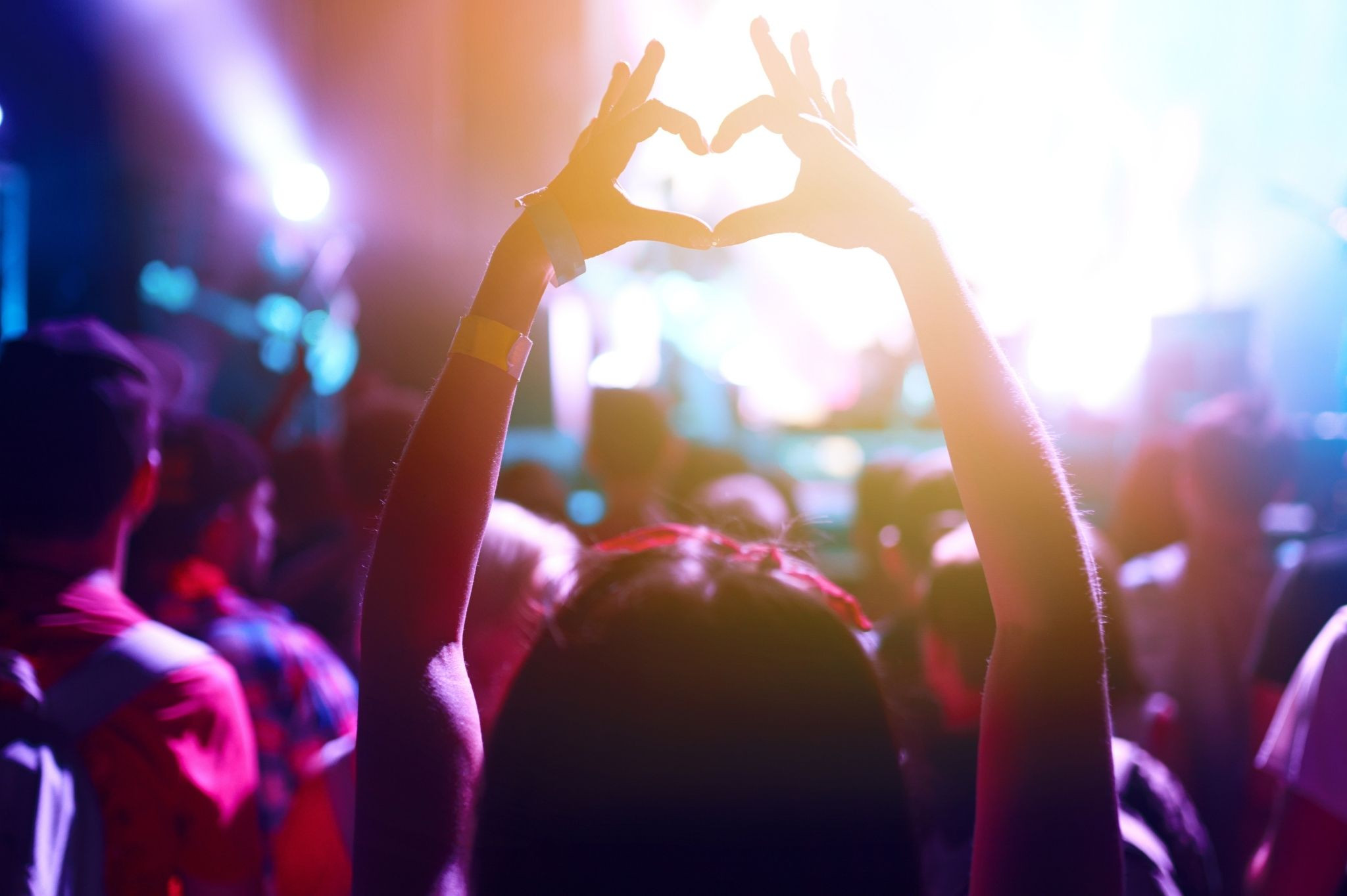 Junge Frau auf einer Summer Party formt mit den Händen ein Herz vor der Bühne
