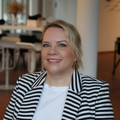 Frauke im gestreiften Blazer in modernem Büro