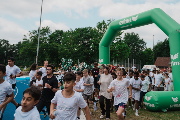 mak-perspektiven-3: Lauf-Event für Kinder und Jugendliche unter Erima-Bogen mit Cheerleadern Kinder und Jugendliche beim mak-perspektiven-3 Lauf-Event unter grünem Erima-Bogen mit Cheerleadern im Hintergrund