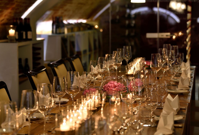Stimmungsvoll gedeckter Tisch mit Kerzen und Blumen im Nobilis Weinkeller
