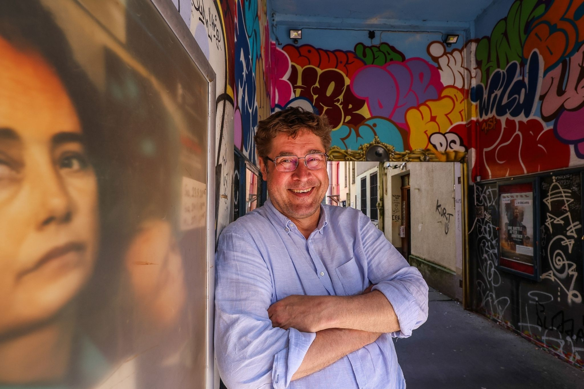 Desimo lächelnd vor bunter Graffitiwand in urbaner Umgebung