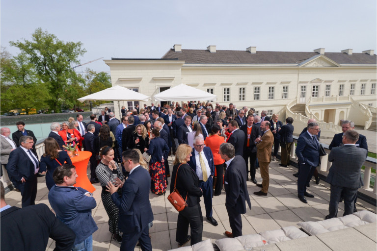 Business-Event auf Terrasse mit vielen Teilnehmern vor historischem Gebäude Große Business-Veranstaltung mit vielen Menschen im Anzug auf einer sonnigen Terrasse vor einem historischen Gebäude