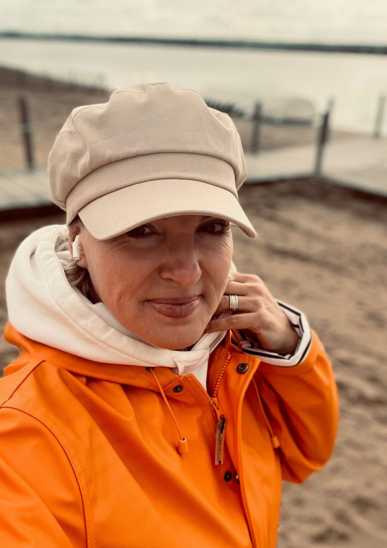 sport-3: Frau mit Mütze und sportlicher Kleidung am Strand Frau mit beiger Mütze und orangefarbener Jacke am Strand, sport-3