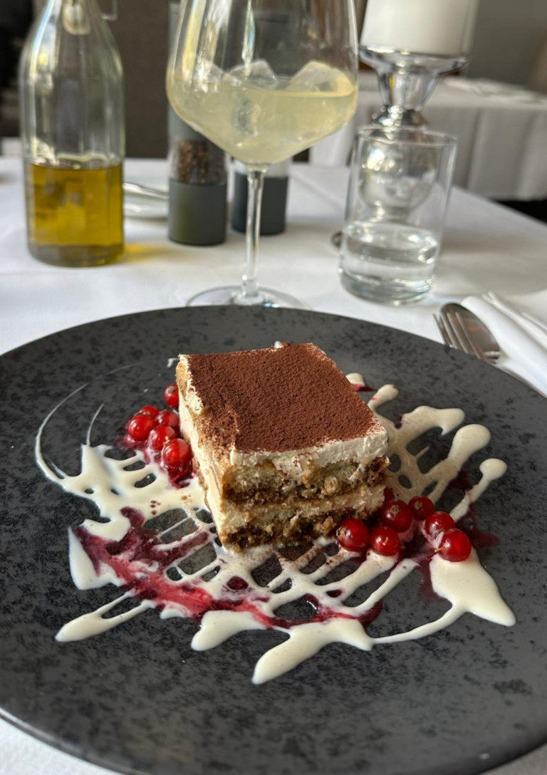Tiramisu im Restaurant Hindenburg – Dessert auf schwarzem Teller mit Johannisbeeren Tiramisu Dessert im Restaurant Hindenburg auf schwarzem Teller mit Johannisbeeren und Soße