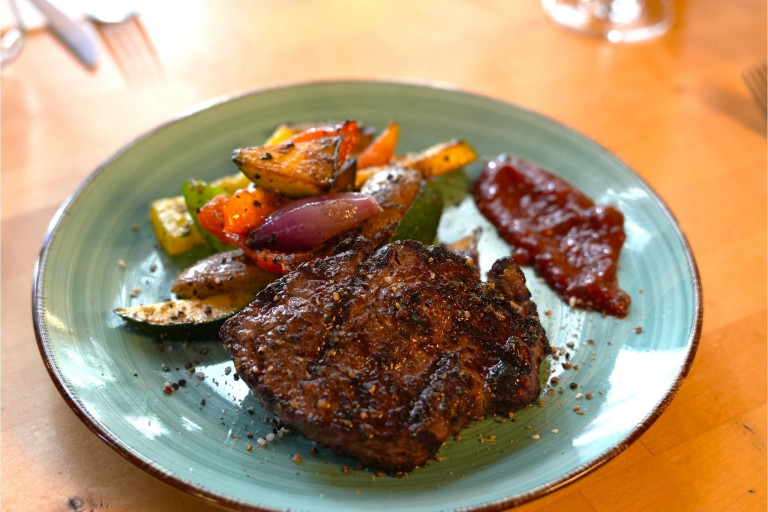 Gegrilltes Steak mit Gemüse und Sauce im Nobilis Restaurant – bilder-nobilis-web-8.jpg Gegrilltes Steak mit Grillgemüse und Sauce auf einem Teller im Restaurant Nobilis