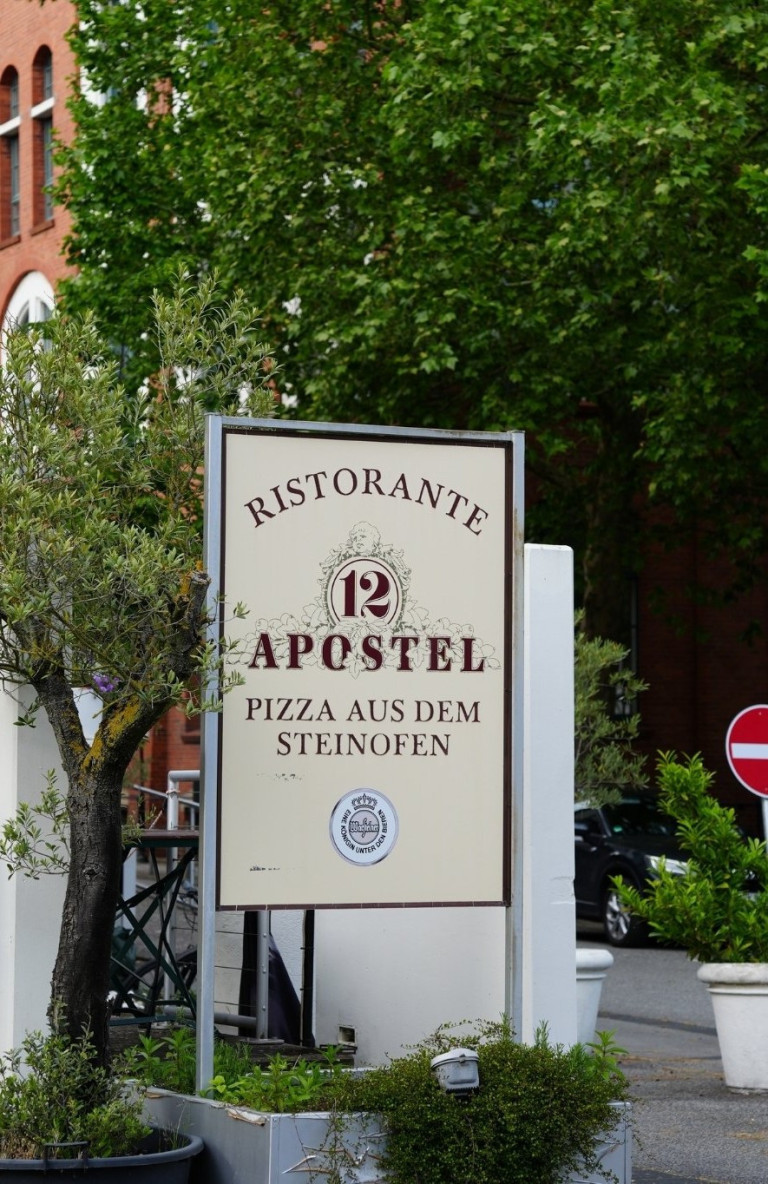 Ristorante 12 Apostel – Pizza aus dem Steinofen im Überblick Eingangsschild des Ristorante 12 Apostel mit Hinweis auf Pizza aus dem Steinofen
