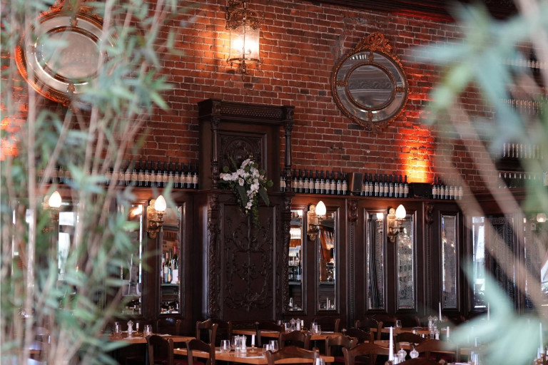 Restaurant Nobilis – stilvolle Innenansicht mit Backsteinwand und eleganter Einrichtung Innenansicht des Restaurants Nobilis mit Backsteinwand, Spiegeln, Holzmöbeln und Weinflaschen