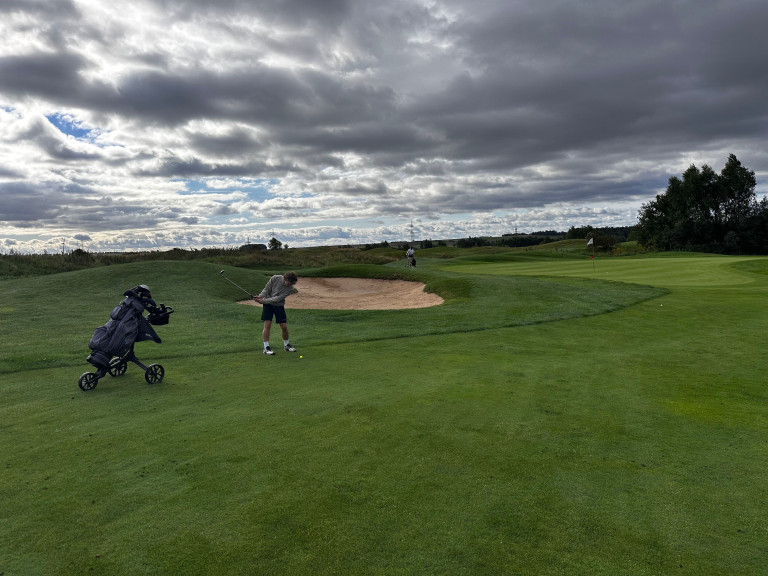 Golfer beim Abschlag auf dem Golfplatz unter bewölktem Himmel – Grasgeflüster: Das richtige Maß