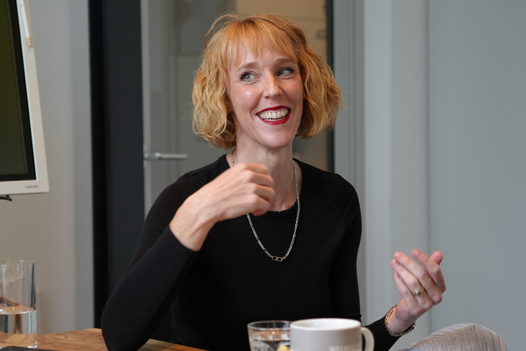 Julia Wohlfeld ist erste Vorsitzende bei Civilia und weiß, nach dem Programm geht niemand mehr mit derselben Haltung durch die Stadt wie zuvor. Frau mit rötlich-blonden, lockigen Haaren lacht bei einem Gespräch am Tisch.
