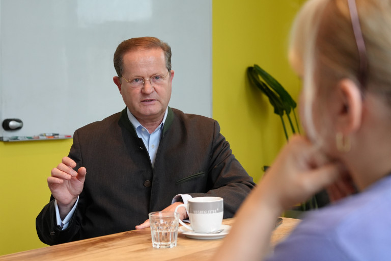 Schatzmeister Valentin Seidenfus im Interview. Valentin Seidenfus im Interview mit einer Tasse Kaffee und Wasserglas am Tisch.