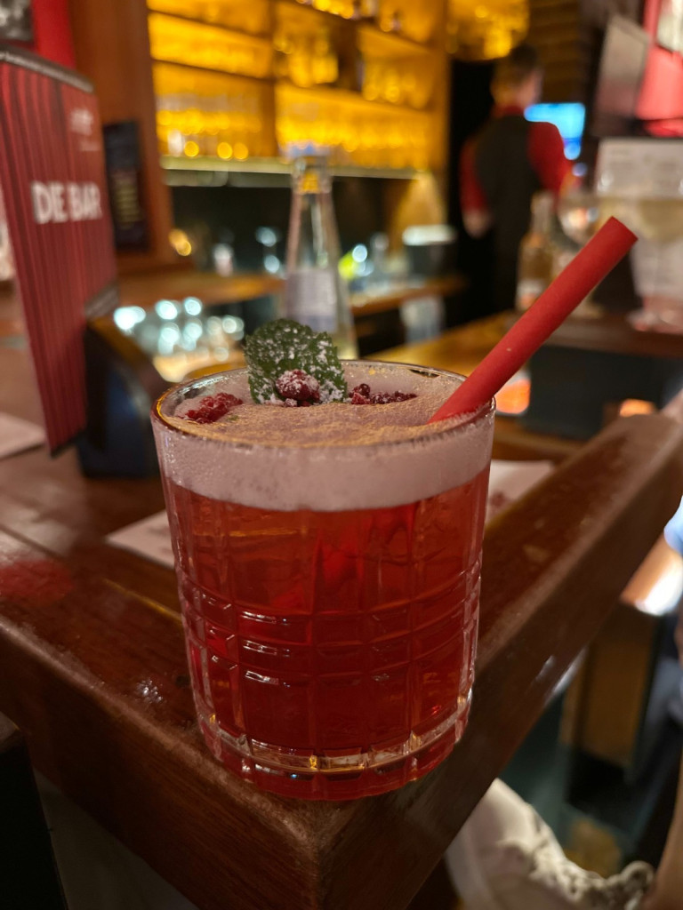 Frank Cocktail in der Neues Theater Bar bei 'Eine Geistergeschichte' – stilvoller roter Drink Frank Cocktail bei 'Eine Geistergeschichte' in der Neues Theater Bar – roter Drink mit Minze und Strohhalm