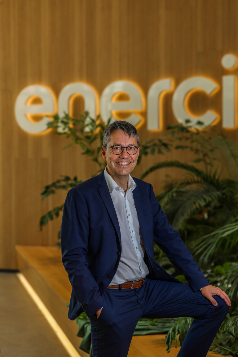 Hansmann Porträt im Büro vor enerci-Logo am 06.08.2026 Hansmann im modernen Büro vor dem enerci-Logo, Porträt am 06.08.2026