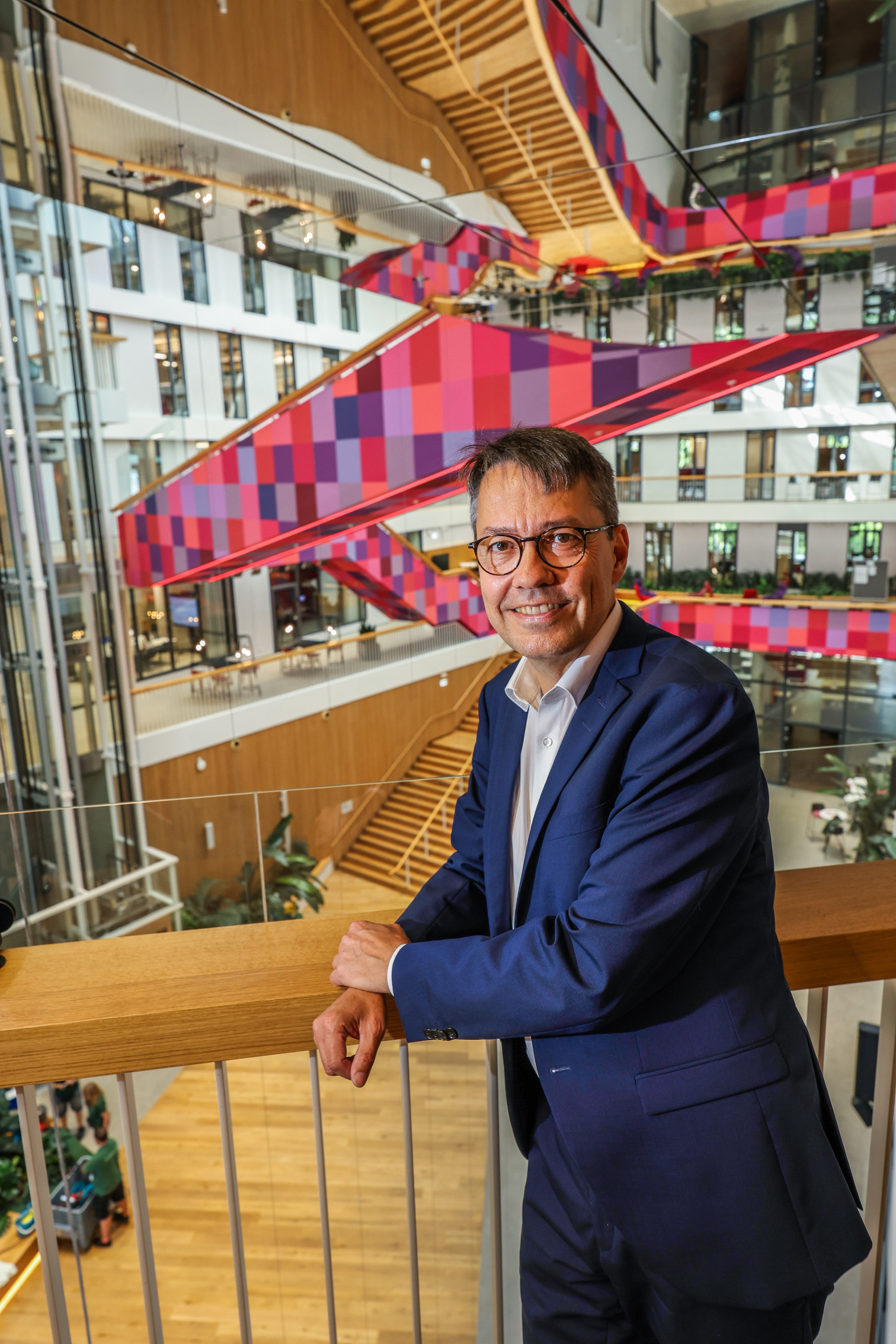 Hansmann in modernem Bürogebäude mit bunter Architektur im Hintergrund
