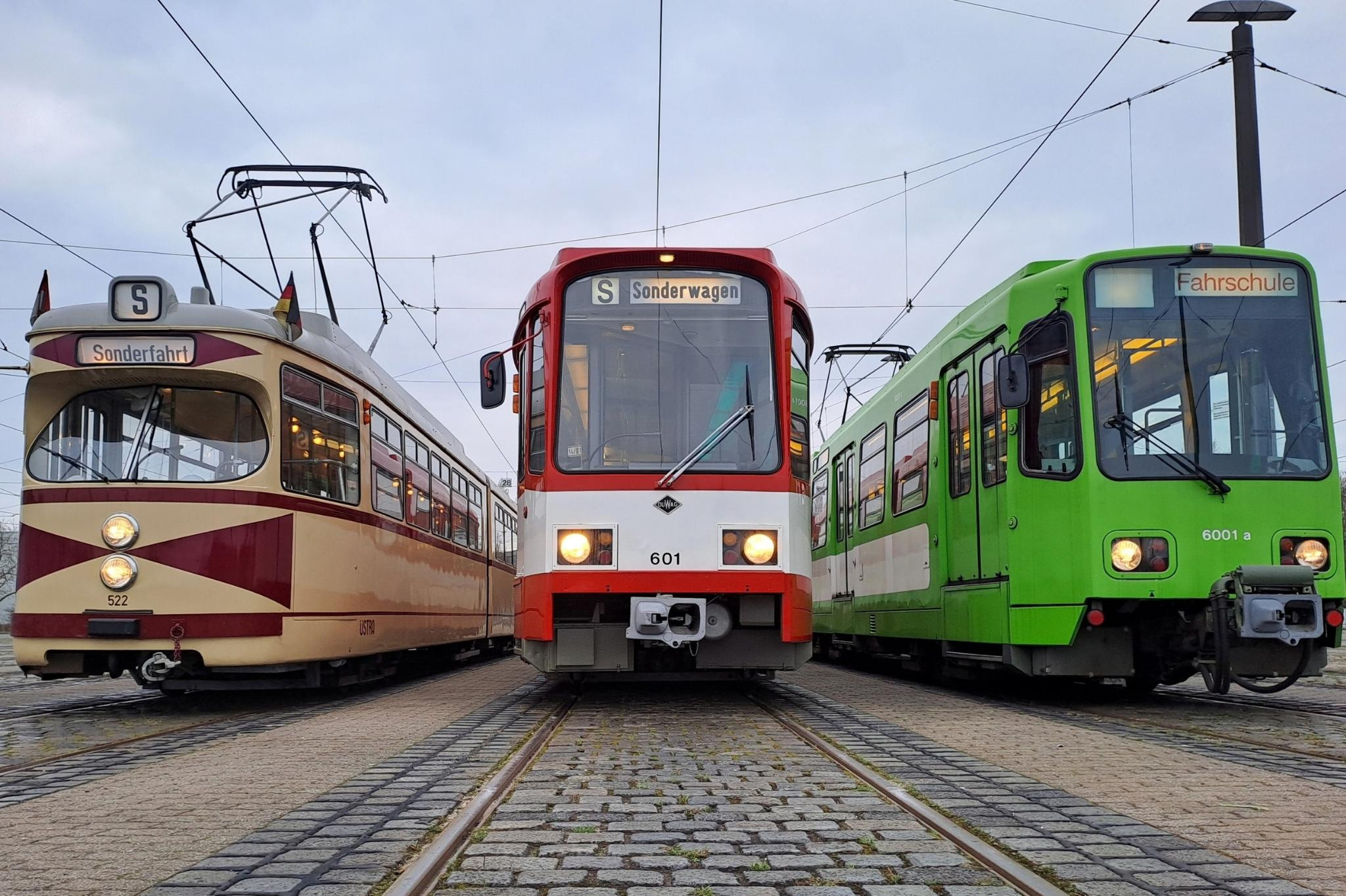 Drei Straßenbahnen verschiedener Bauarten auf einem Gleis, zentrale Ansicht, mit Sonderwagen-Beschilderung.