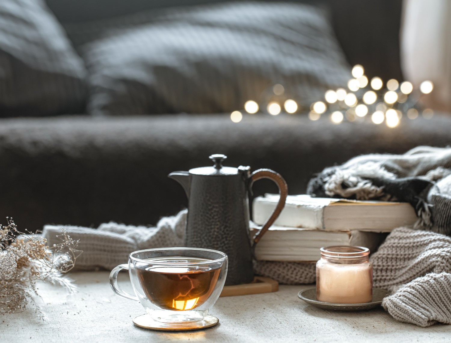 Gemütliche Cocooning-Atmosphäre in Hannover mit Tee, Kerze und Büchern auf einem Sofa
