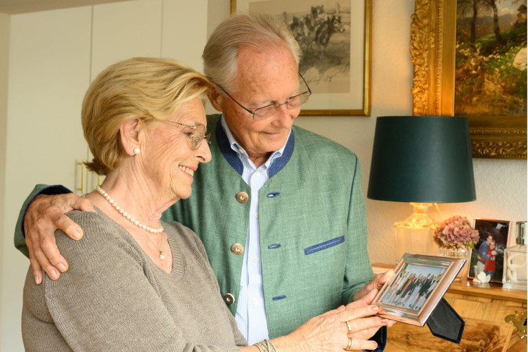 Älteres Ehepaar betrachtet gemeinsam ein Familienfoto – Symbol für lange Liebe und Partnerschaft