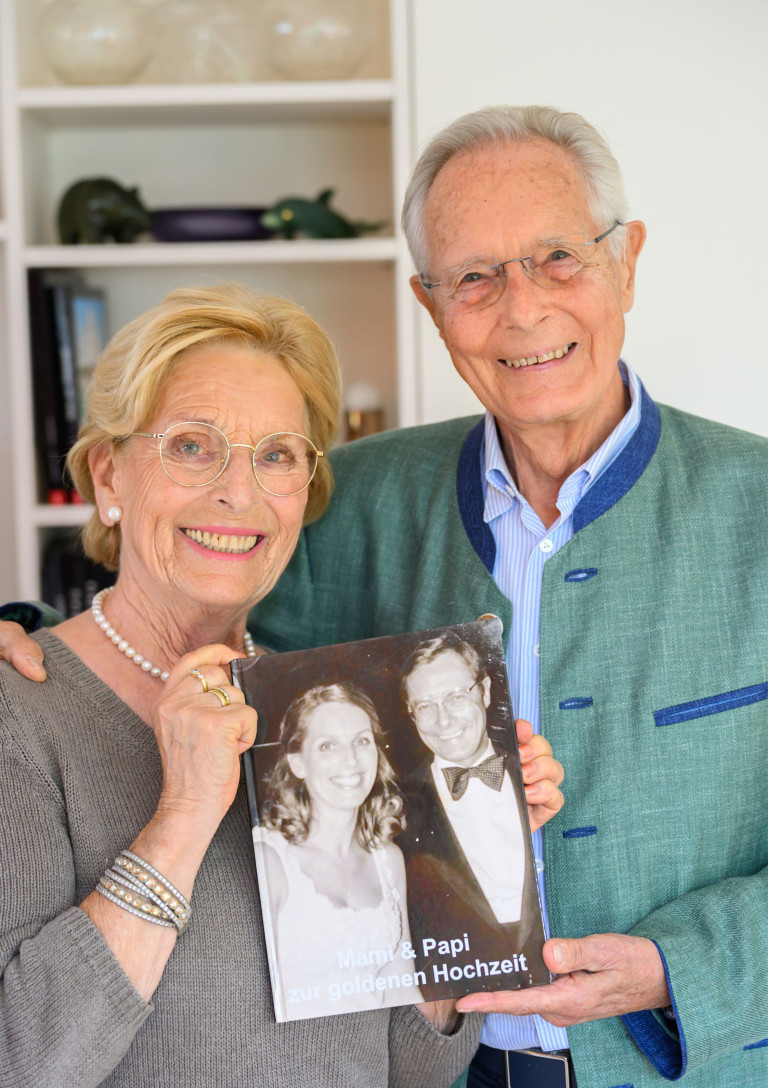 Älteres Paar hält ein altes Hochzeitsfoto – Symbol für lange Liebe und beständige Partnerschaft