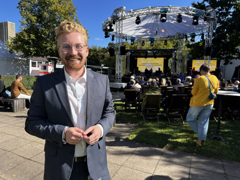 Mann im Anzug bei der liminale 2026 vor Open-Air-Bühne mit Publikum