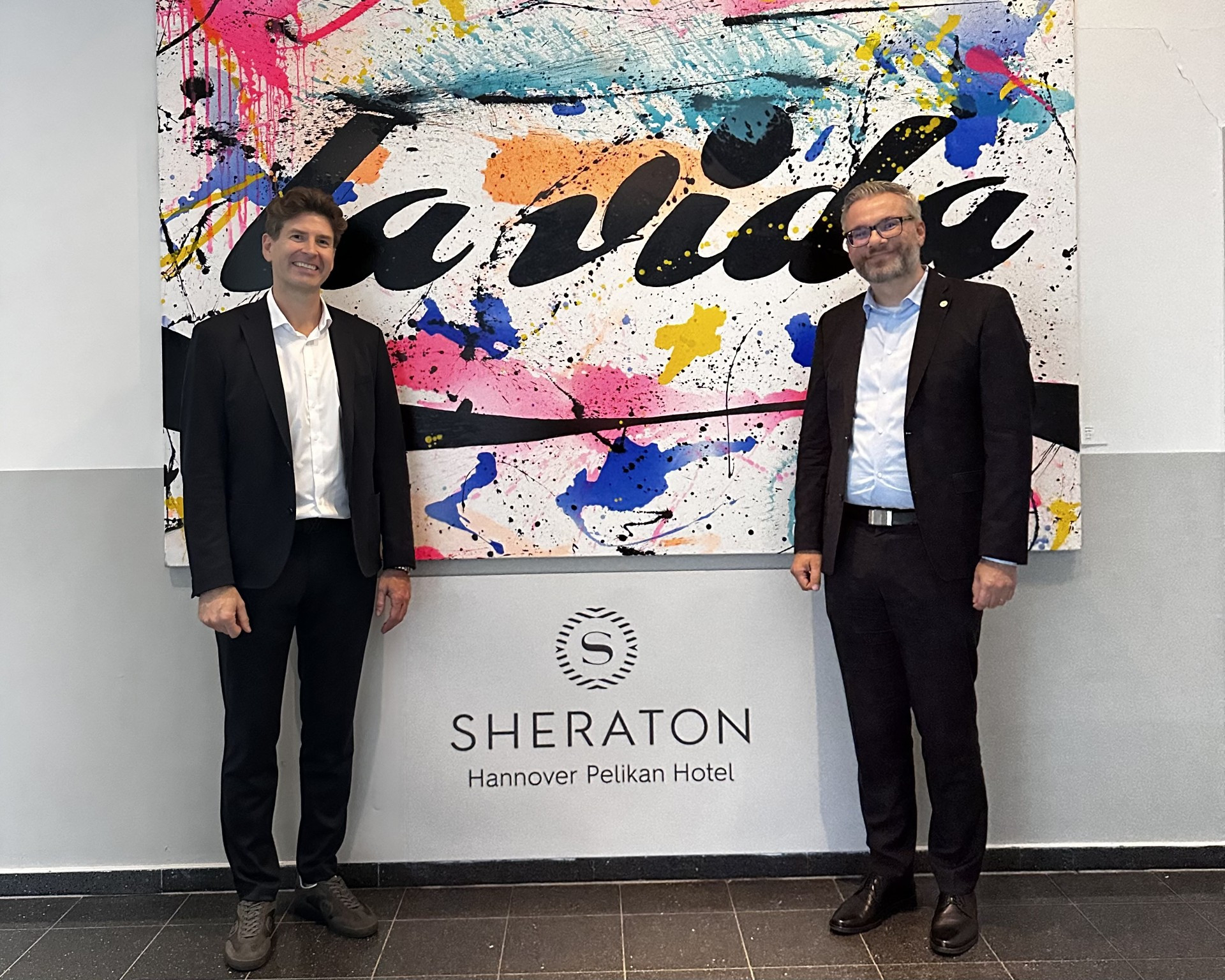 Sascha Dahl und Sebastian Krebs im Sheraton Hannover Pelikan Hotel vor dem Kunstwerk 'la vida'