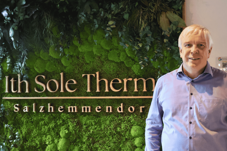 Christoph van Bebber vor grüner Pflanzenwand mit Schriftzug Sole Therme – Saunieren in Bad Salzhemmendorf