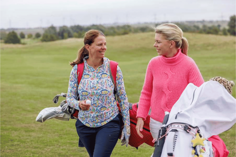 Zwei Frauen beim Golfspielen auf dem Golfplatz, fröhlich und entspannt mit Golfausrüstung.