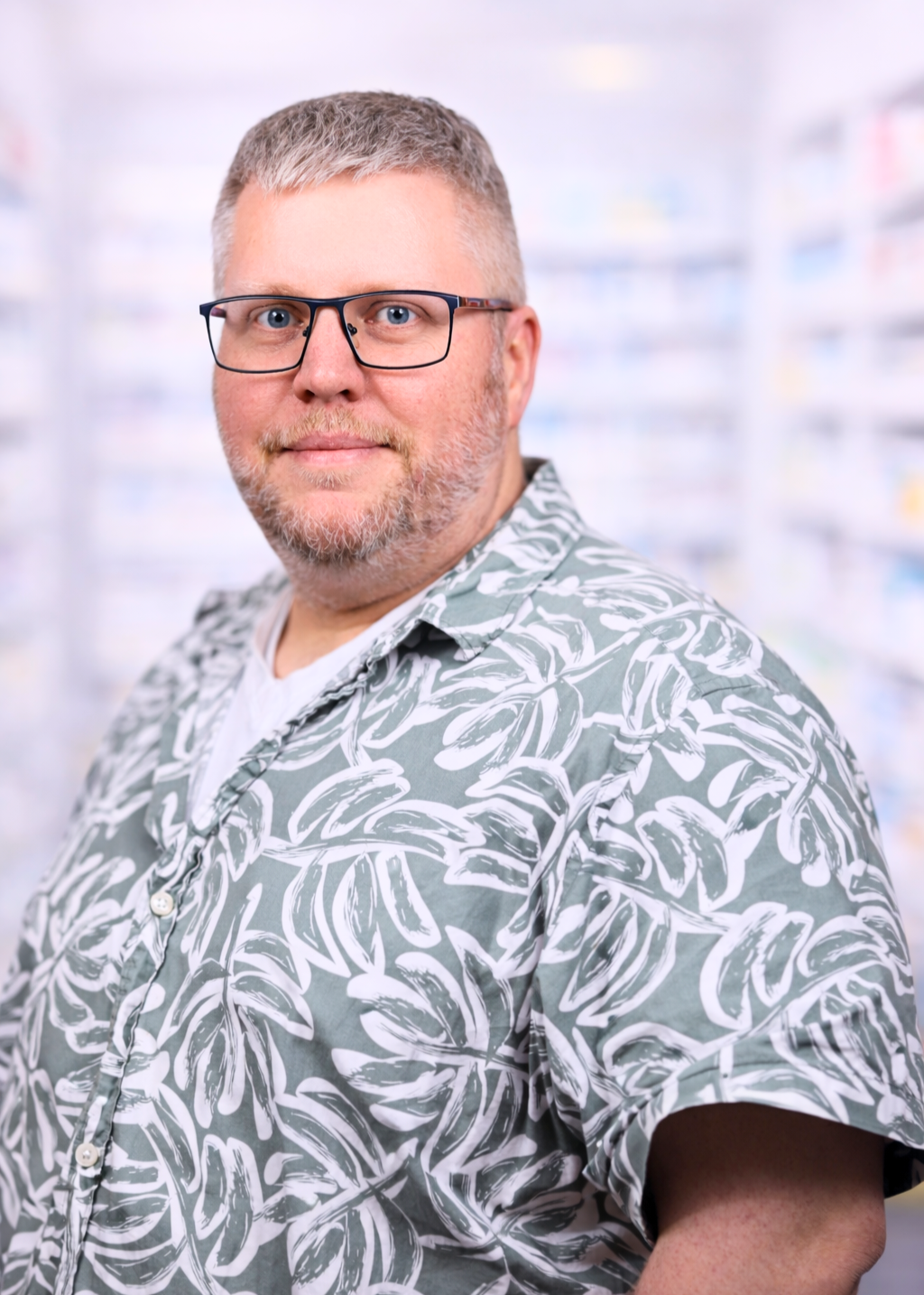 Porträt von Bludau mit Brille und gemustertem Hemd vor unscharfem Hintergrund