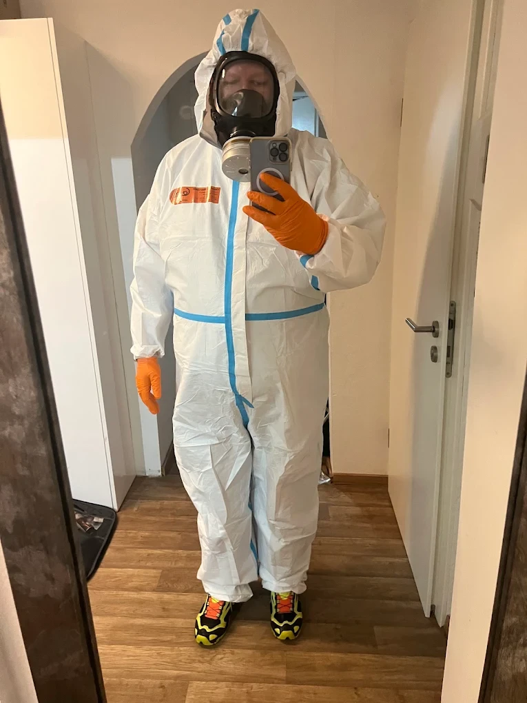 Person im Schutzanzug mit Atemmaske und Handschuhen