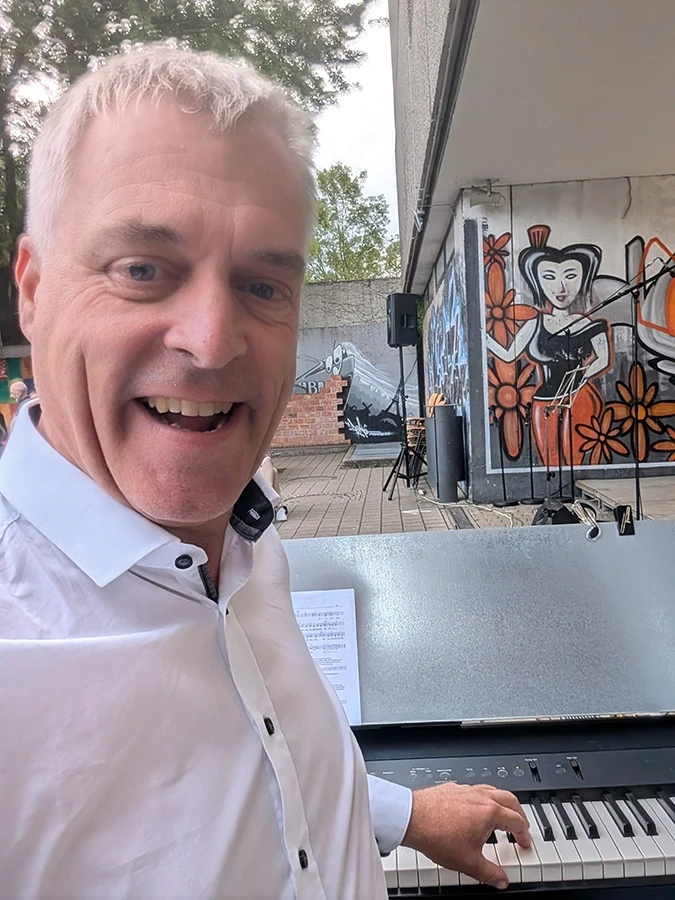Mann am Klavier vor Graffiti-Kunstwerk Mann spielt Klavier vor Graffiti mit Straßenkunstmotiv