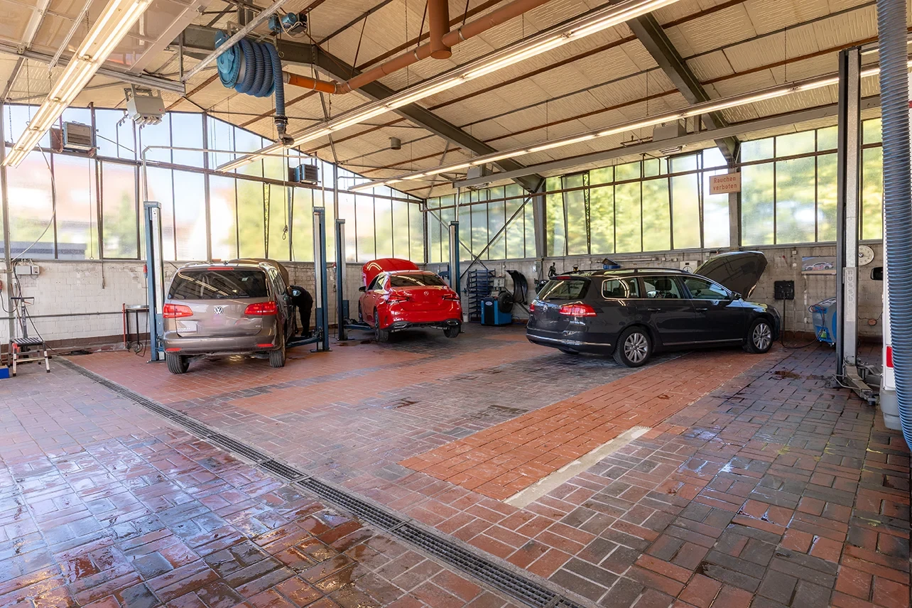 Innenansicht einer modernen Autowerkstatt mit mehreren Fahrzeugen auf Hebebühnen