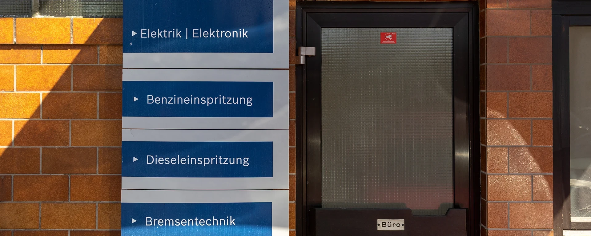 Eingang mit Bürotür und Schildern zu Elektronik, Einspritzung und Sensortechnik
