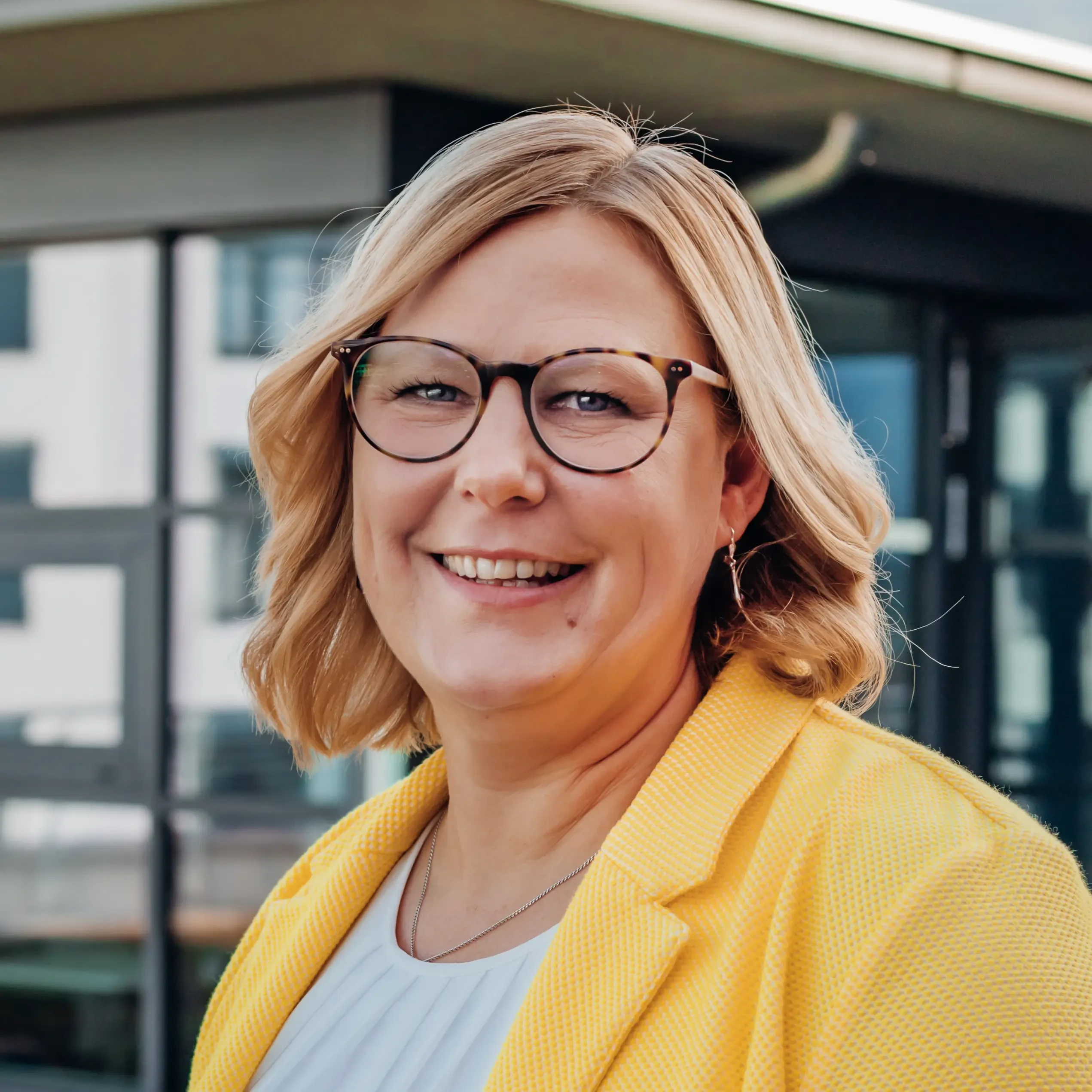 Porträt von Sandra Janda im gelben Blazer