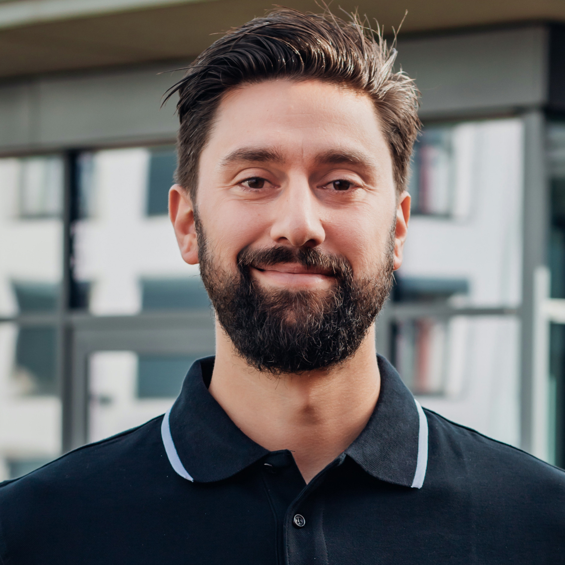 Vincenzo Kanat im schwarzen Polohemd vor modernem Gebäude