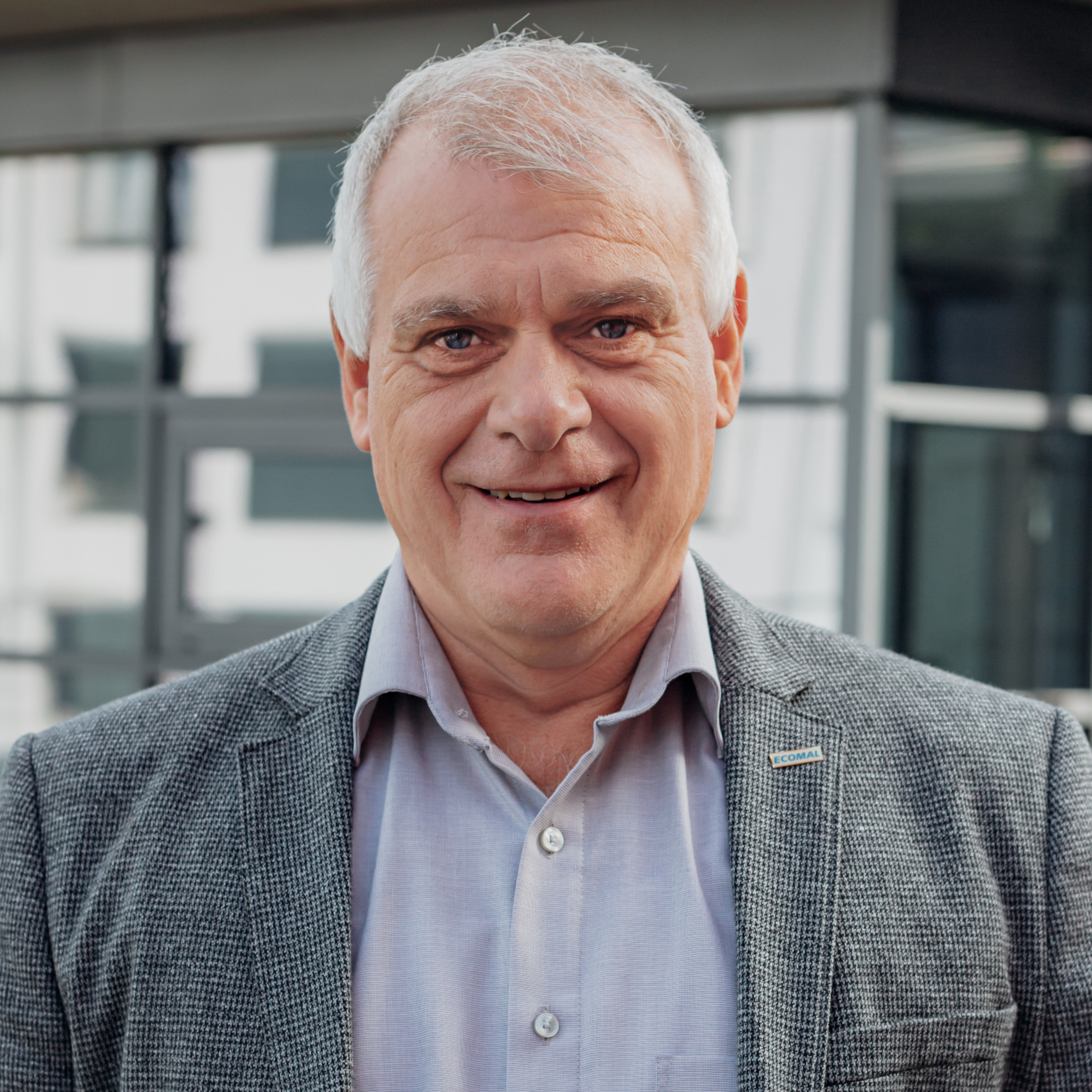 Peter Kraus im grauen Sakko vor modernem Gebäude