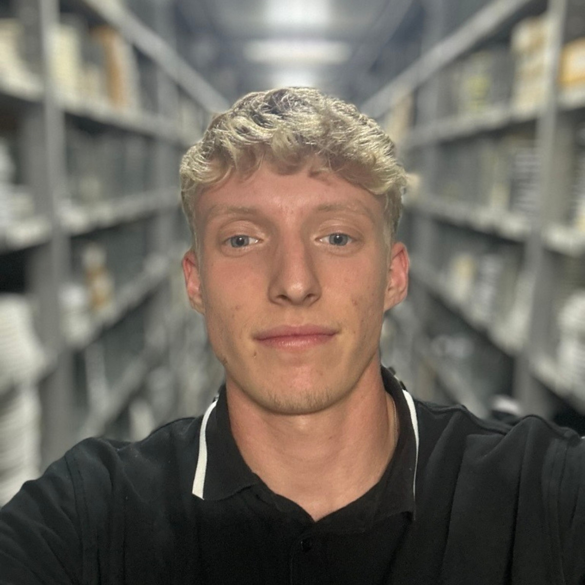 Janek Hillenbrand in einem Lager mit Regalen im Hintergrund