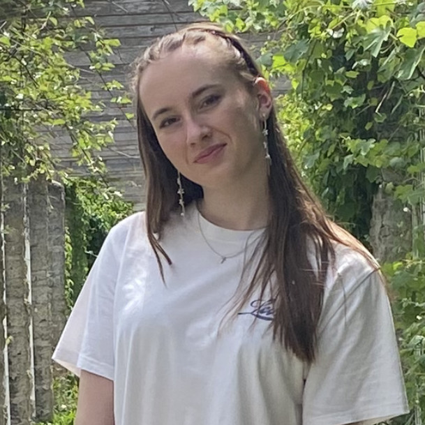 Pia Schweizer im weißen T-Shirt vor einer grünen Naturkulisse