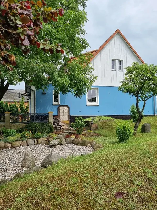 Blaues Haus mit Garten und Kiesweg Blaues Haus mit gepflegtem Garten und Kiesweg