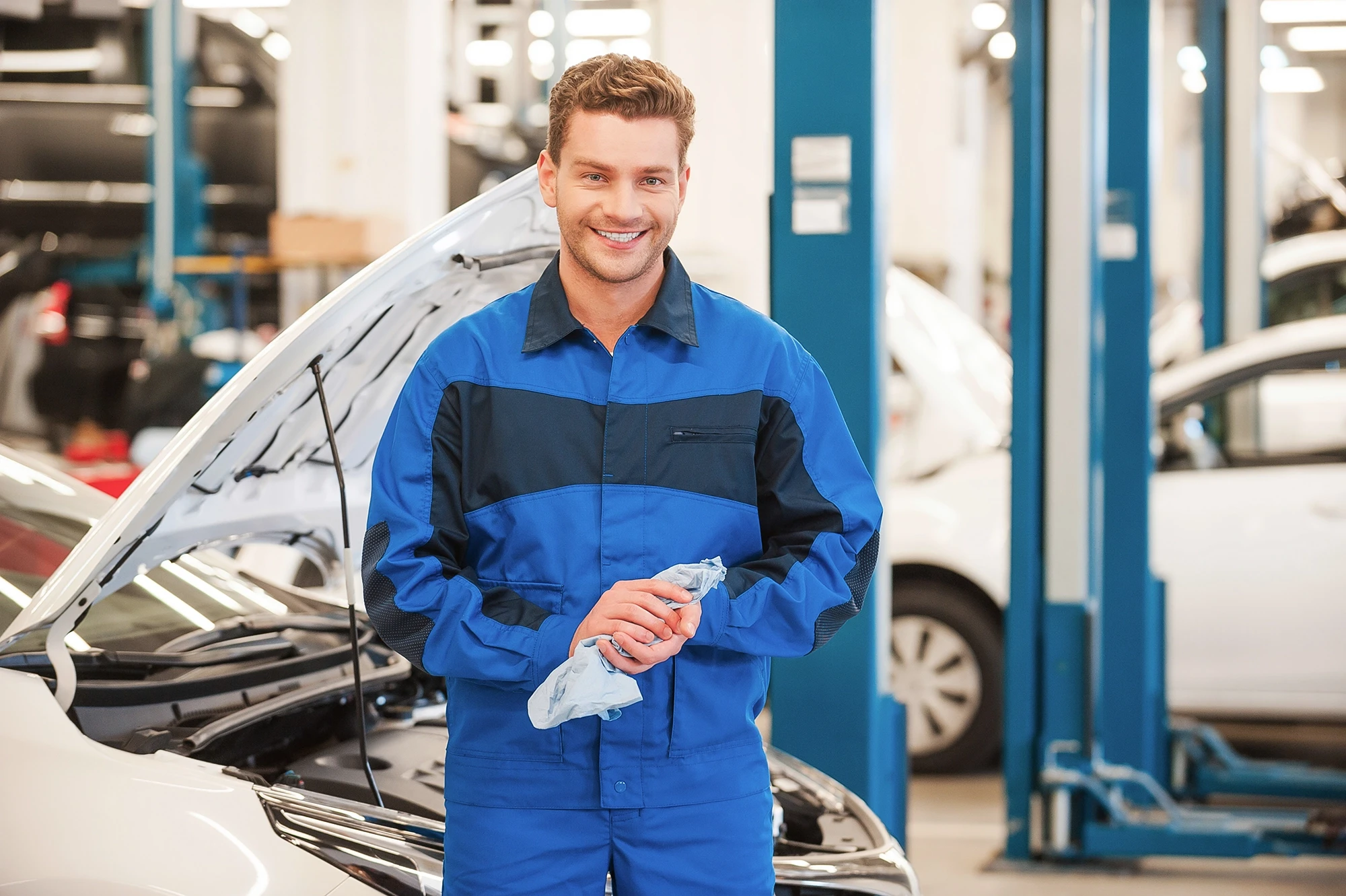 Automechaniker in Werkstatt mit blauer Arbeitskleidung Automechaniker in blauer Arbeitskleidung in einer Werkstatt