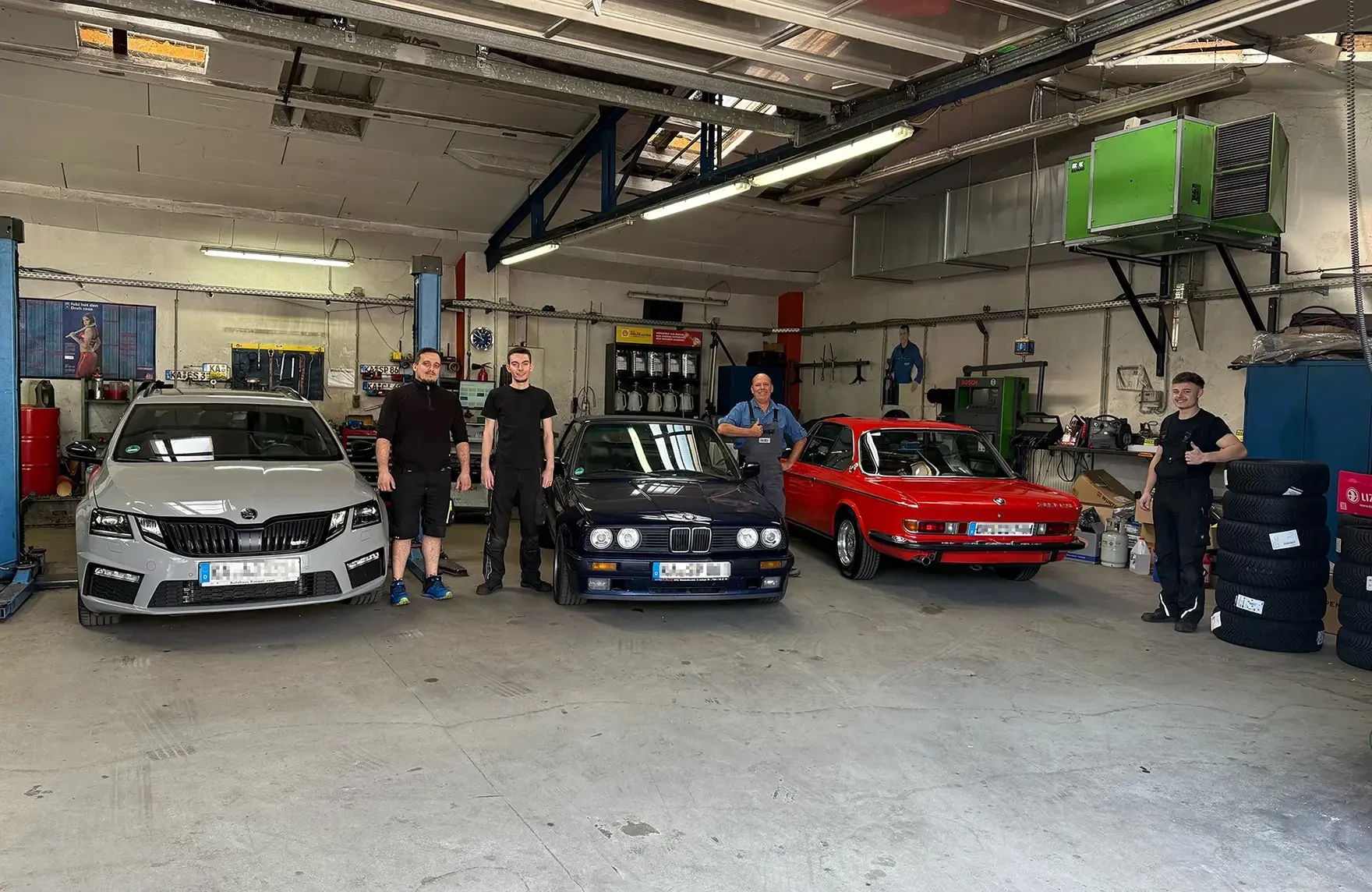 Autowerkstatt mit verschiedenen Fahrzeugen und Mechanikern in der Werkstatt Innenansicht einer Autowerkstatt mit drei Autos und Mechanikern