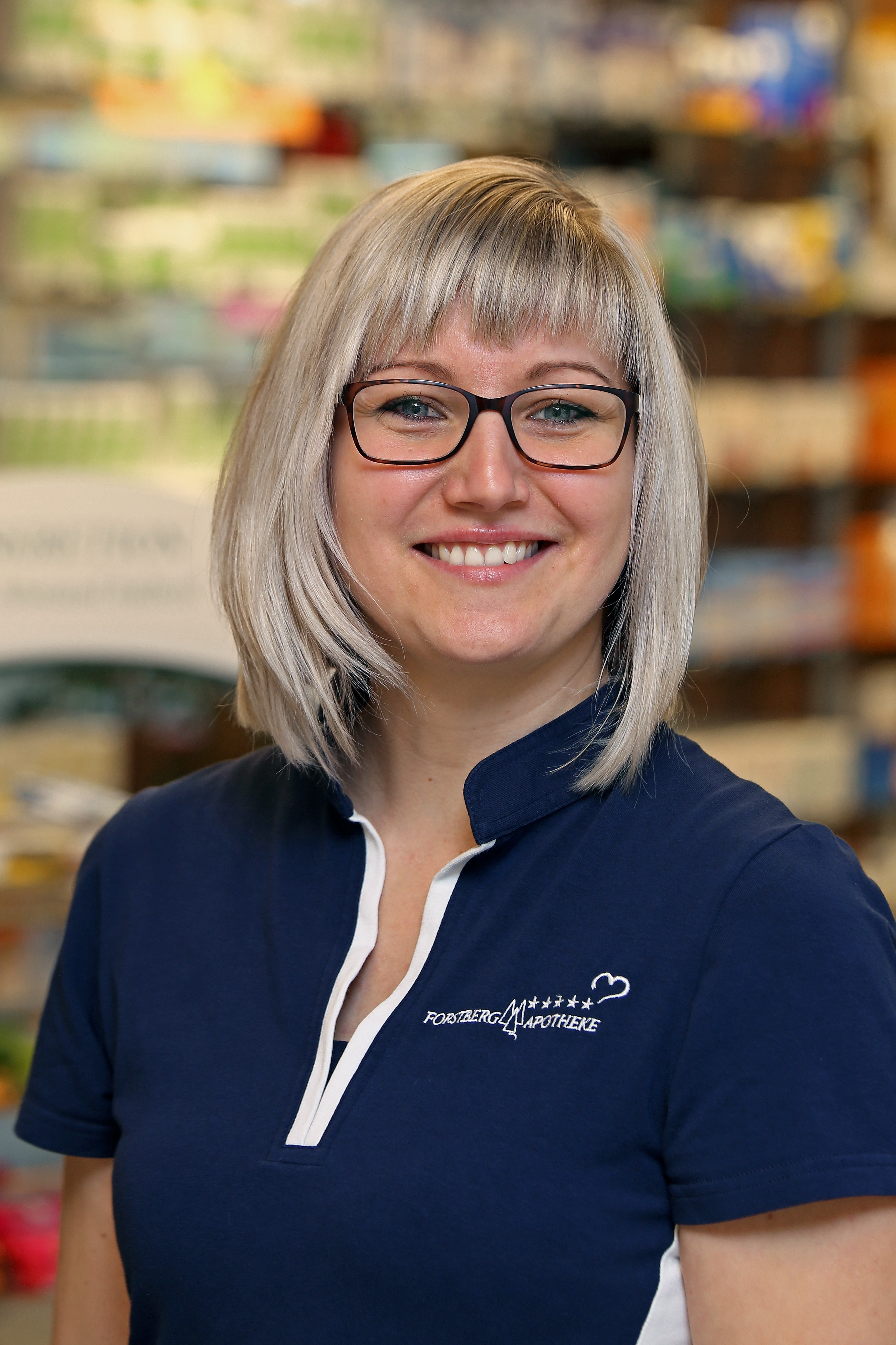 Porträt einer lächelnden Apothekerin mit Brille in der Apotheke