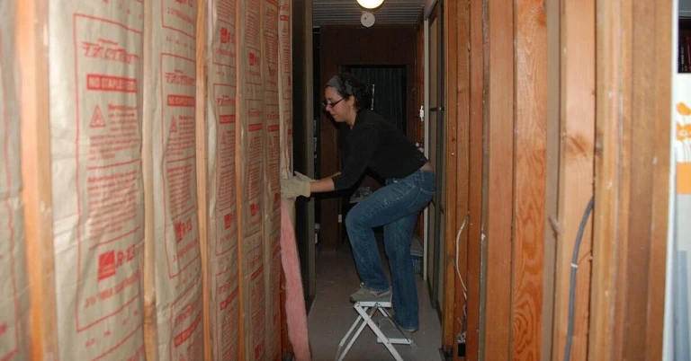 Installation von Dämmmaterial in einem Gebäude Person bei der Installation von Dämmmaterial in einem Gebäude