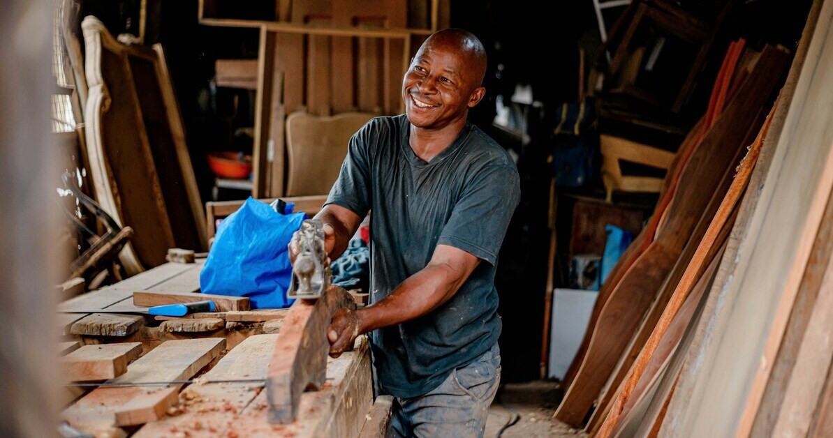 Junger Schreiner beim Hobeln von Holz in der Werkstatt Junger Schreiner hobelt Holz in einer Werkstatt